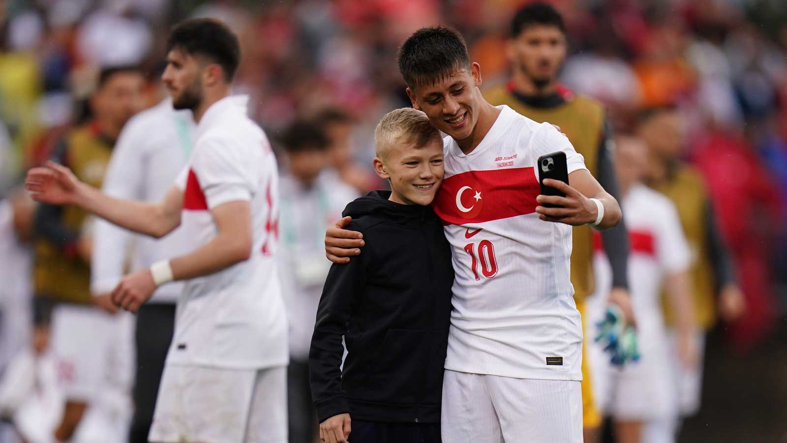 A soccer fan runs onto the field to get a photo with Turkey forward Arda Güler (10) after the game against team USA in the second half at Pratt & Whitney Stadium at Rentschler Field.