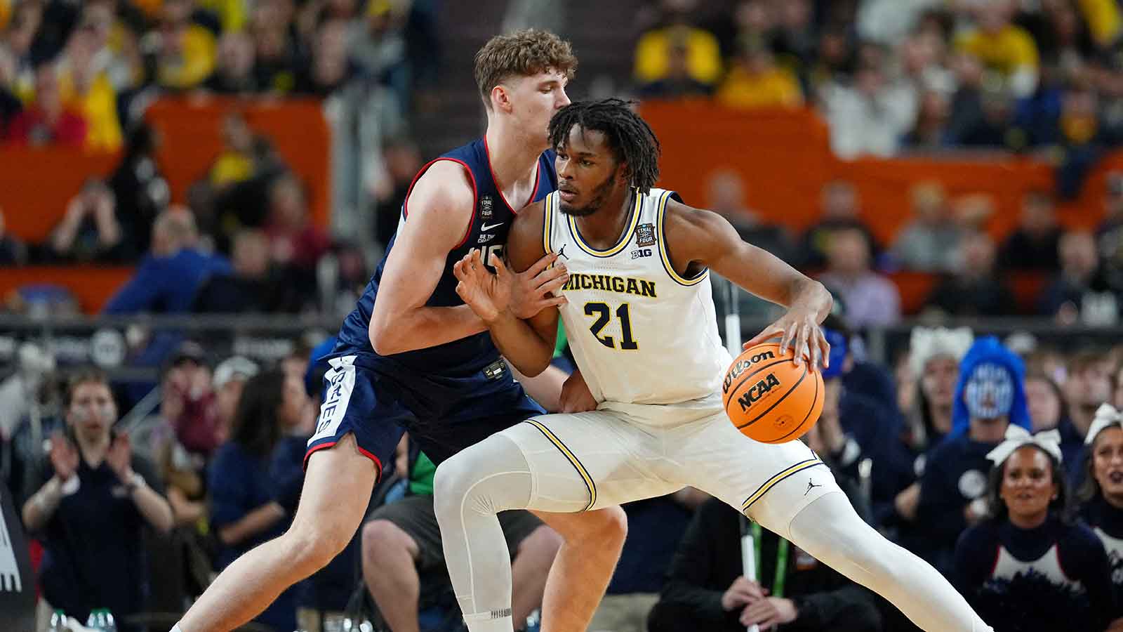 Michigan Wolverines forward Morez Johnson Jr. (21) controls the ball against UConn Huskies center Eric Reibe (12) during the first half in the national championship of the Final Four of the men's 2026 NCAA Tournament between the  and the Michigan Wolverines at Lucas Oil Stadium. 