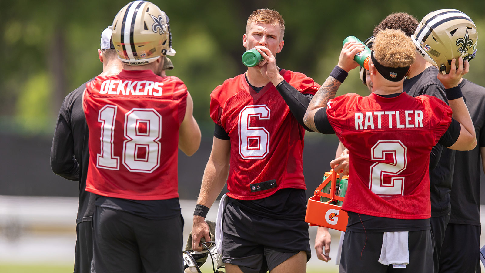New Orleans Saints quarterbacks Tyler Shough (6), Spencer Rattler (2) and Hunter Dekkers (18) take a water break