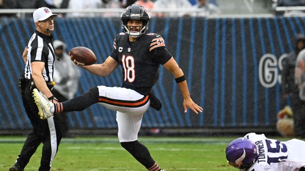 Chicago Bears quarterback Caleb Williams (18) runs from Minnesota Vikings linebacker Dallas Turner (15) during the first half at Soldier Field.